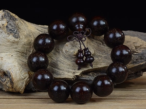 Macro detail of sandalwood beads with golden star patterns and decorative gourds