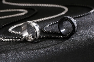 Macro view of rotating stainless steel mantra ring pendants in silver and black colors
