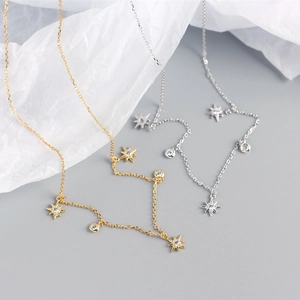 Detail shot of silver and gold S925 necklaces with star and circle pendants on paper
