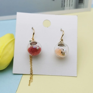 Colorful glass ball earrings with tassels and beads on decorative floral background