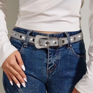 Fashionable silver rhinestone belt with western buckle on blue jeans for women