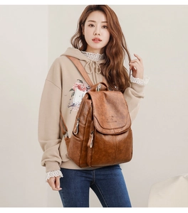 Detail of dark brown leather backpack featuring a kangaroo logo and side zipper pocket