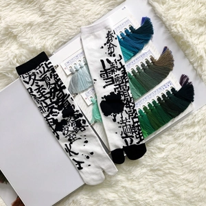 Detail of two pairs of Tabi socks with black and white calligraphy patterns on soft plush fabric