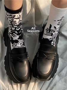 Detailed close-up of black matte leather loafers paired with Chinese calligraphy socks