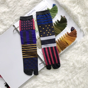 Close-up of Tabi socks with vibrant geometric patterns on white textured background