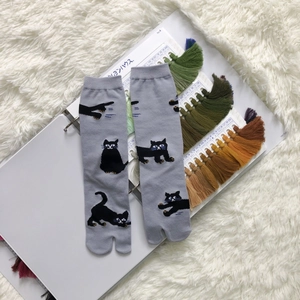 Detail of grey Tabi socks featuring black cat jacquard patterns on soft plush background