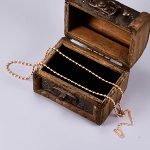 Macro detail of 18K gold bead necklace with K18 hallmark on a vintage wooden case
