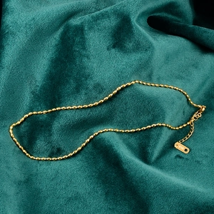 Minimalist 18K gold-plated stainless steel olive bead necklace on green velvet