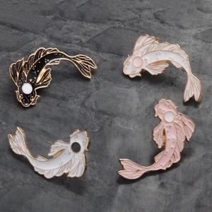 Set of four colorful koi fish enamel pins with gold metal borders on a stone background