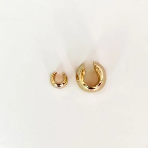 Detail of minimalist gold spherical ear cuffs showing polished metallic finish and C-shape
