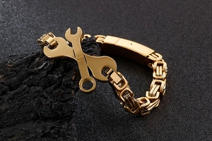 Détail d'un bracelet industriel doré en forme de clé sur un fond de roche sombre