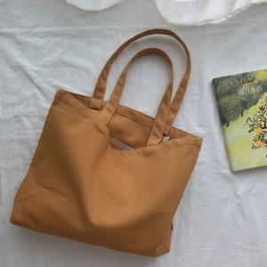 Sac fourre-tout minimaliste en toile marron gingembre, vue de dessus sur tissu blanc