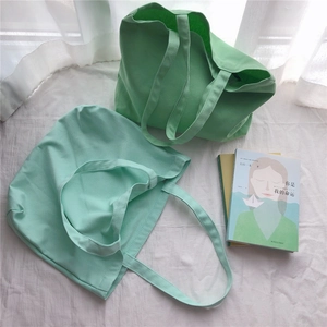 Sacs cabas en toile vert émeraude et vert menthe sur un fond en tissu blanc doux