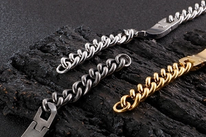 Macro shot of silver, gold and black Cuban link bracelets on a dark wood texture