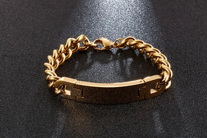 Close-up of golden stainless steel ID bracelet with curved plate on black background