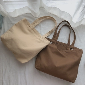 Gros plan de sacs cabas en toile beige et marron montrant la texture du tissu fin