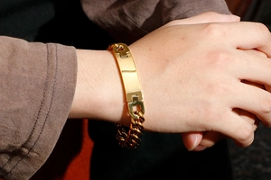 Close-up of a men's gold stainless steel ID bracelet worn on a wrist showing the smooth plate