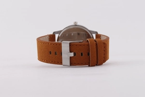 Détail du bracelet de montre en daim marron avec boucle argentée et coutures de précision