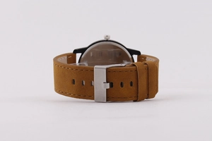 Gros plan du bracelet en daim marron avec boucle argentée et boîtier de montre noir