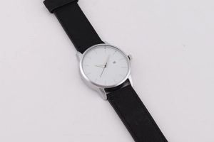 Détail d'une montre à quartz avec cadran blanc, guichet de date et bracelet cuir noir