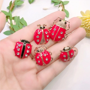 Close-up of five red ladybug brooches with gold plating and sparkling rhinestones