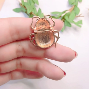 Golden metal ladybug insect brooch showing the back pin mechanism and polished finish