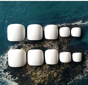 Detailed set of white press-on toenails in various sizes displayed on a coastal rock background