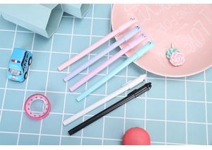 Set of six colorful cat-themed gel pens arranged diagonally on a blue grid background