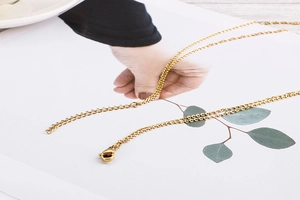 Detail of gold double-layer necklace showing lobster clasp and extension chain on card