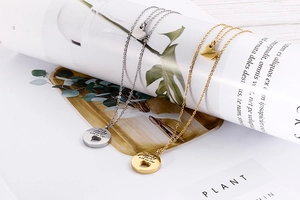 Detail of silver and gold heart necklaces engraved with Every journey starts with one step