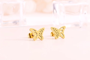 Close-up of golden hollow butterfly stud earrings with elegant cutout metal details