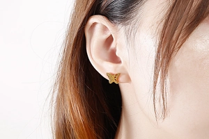 Close-up of elegant gold hollow butterfly stud earrings worn on a model's ear