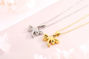 Detail view of elegant dragonfly necklaces in gold and silver finishes on pink background