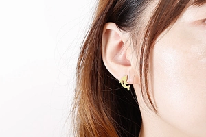 Close-up of a minimalist golden fish-shaped stud earring worn on the earlobe