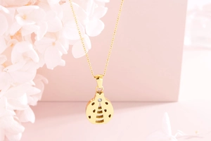 Macro shot of gold ladybug pendant with cut-out dots and sparkling gemstone detail