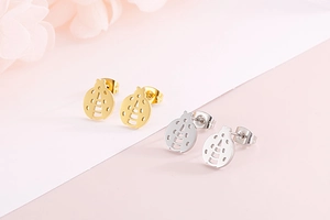 Close-up of gold and silver ladybug stud earrings on a soft pink and white background