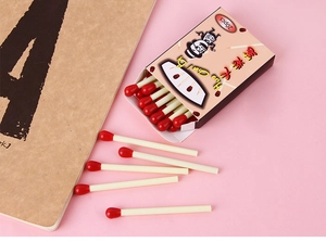 Close-up of creative matchstick-shaped ballpoint pens on pink background with notebook