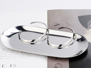 Minimalist silver cuff bracelets on a metal tray with stylish book background details