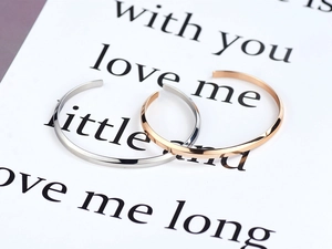 Detail of minimalist silver and rose gold open C-shaped titanium steel couple bracelets