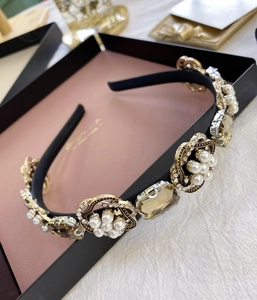Détail d'un serre-tête baroque avec perles, cristaux et gemmes ambrées dans un coffret