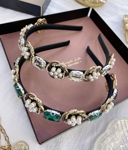 Détail de serre-têtes baroques avec perles, strass et pierres d'émeraude dans une boîte