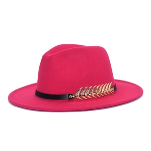 Close-up of rose red fedora hat featuring a black leather band and gold leaf ornament