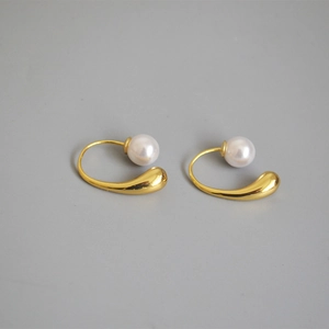 Detail of elegant gold-plated water drop earrings with teardrop metal and round pearl
