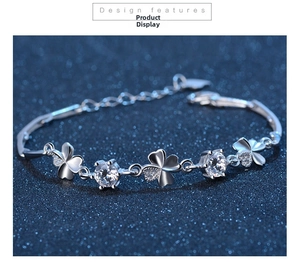 Macro shot of silver S925 clover bracelet with sparkling zircons on blue background