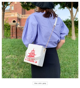 Detail of white PU leather crossbody bag featuring red pagoda print and gold chain strap