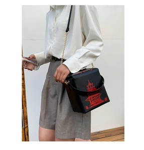 Detailed view of black take-out box style crossbody bag with red pagoda print and gold chain