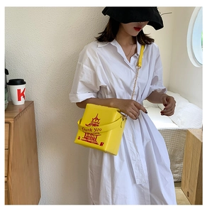 Detail of yellow Chinese takeout box crossbody bag with red tower print and metal chain
