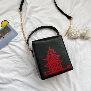 Detail of black box-shaped crossbody bag with red Chinese pagoda print and gold chain strap
