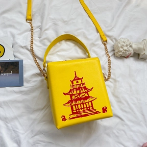 Close-up of a yellow PU leather crossbody bag with a distinctive red pagoda tower print