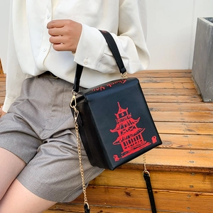 Detail of black crossbody bag featuring a red Chinese pagoda print and gold chain strap